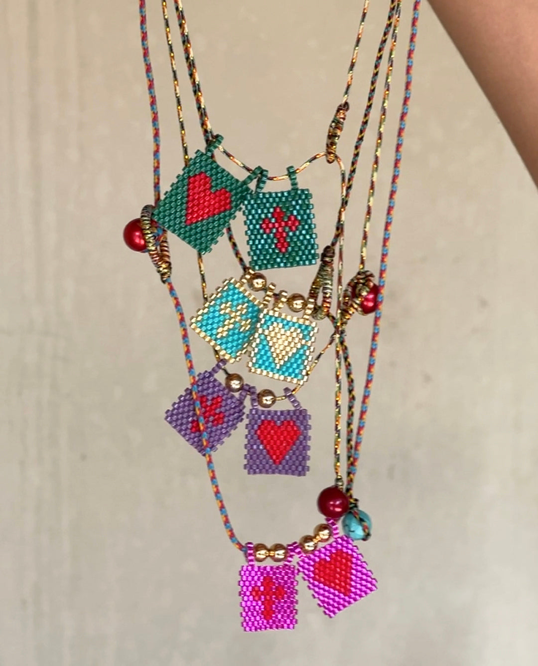 Colorful beaded necklaces with heart and flag charms on a neutral background